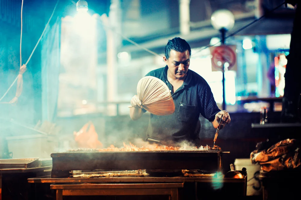 Satay cook tending a grill at night